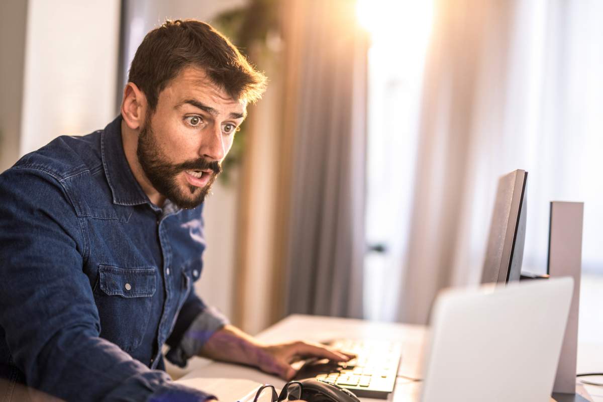 A businessman reads a shocking email on his laptop