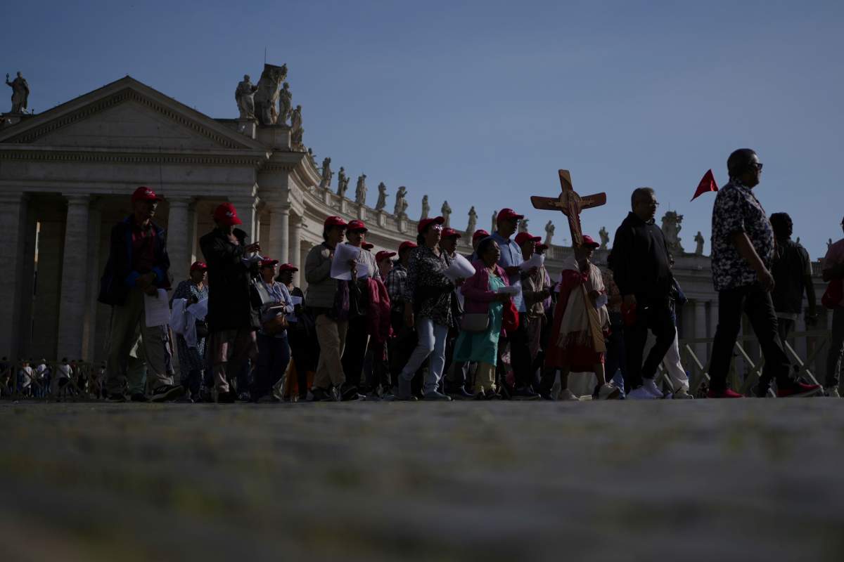 Pilgrims carrying a cross make their way to the Holy Door in St. Peter’s Square at the Vatican after Cardinal Camerlengo Kevin Joseph Farrell announced the death of Pope Francis, Monday, April 21, 2025.