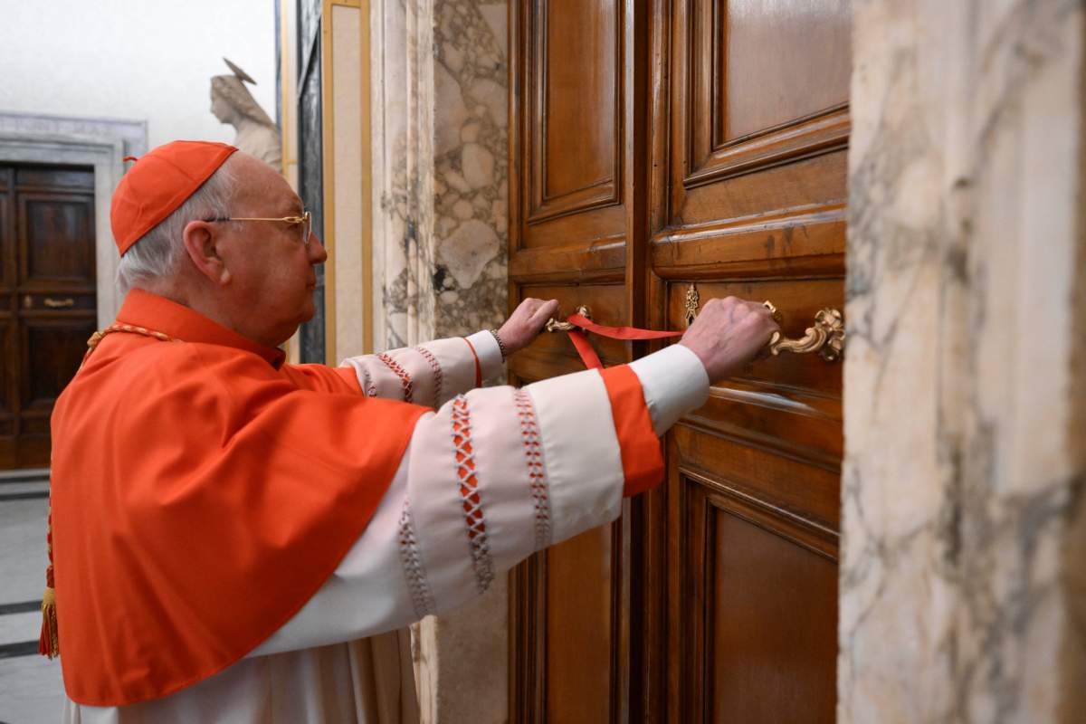 Cardinal Camerlengo Kevin Joseph Farrell seals the door to the papal bedroom and studio at the Vatican after the announcement of the death of Pope Francis, Monday, April 21, 2025.