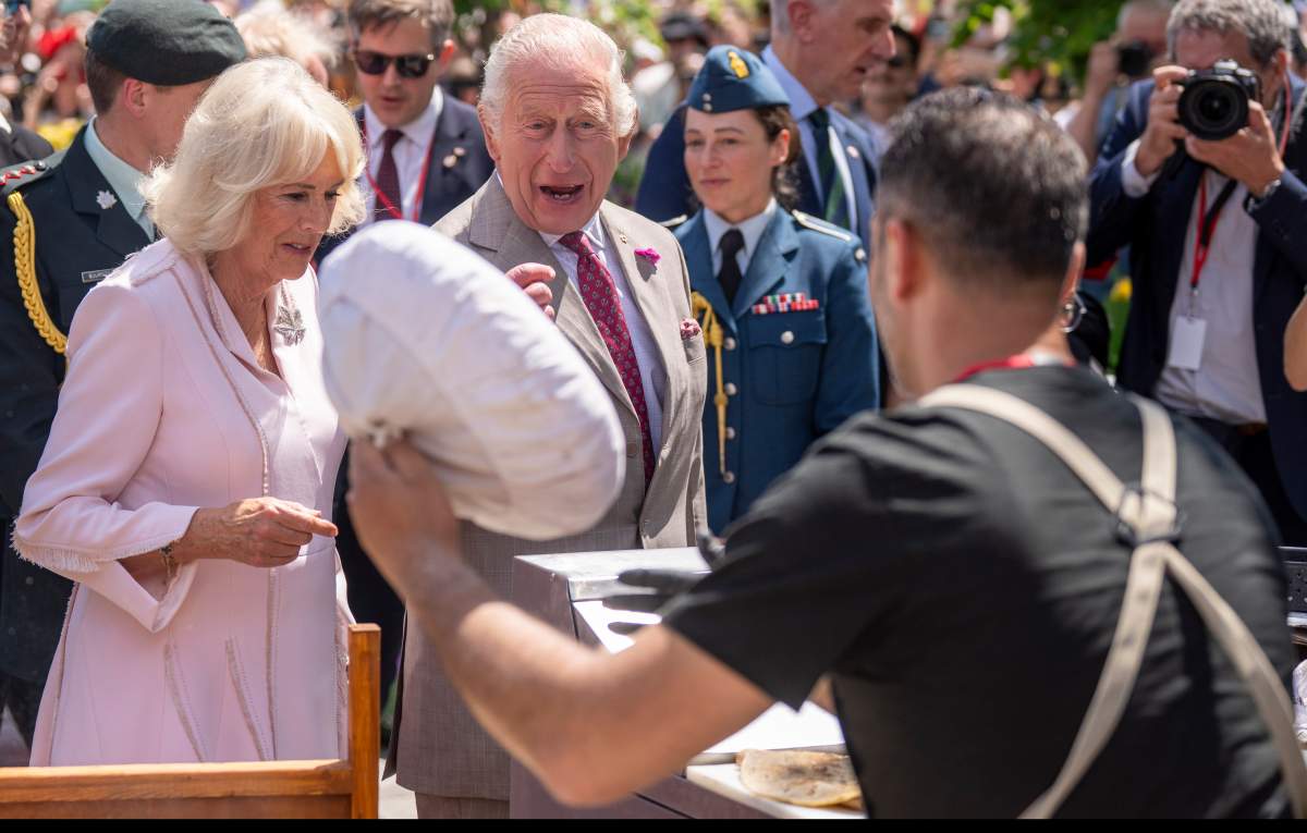 King Charles and Queen Camilla watch a falafel vendor in action during a visit to Lansdowne Park in Ottawa on Monday, May 26, 2025. THE CANADIAN PRESS/Christinne Muschi