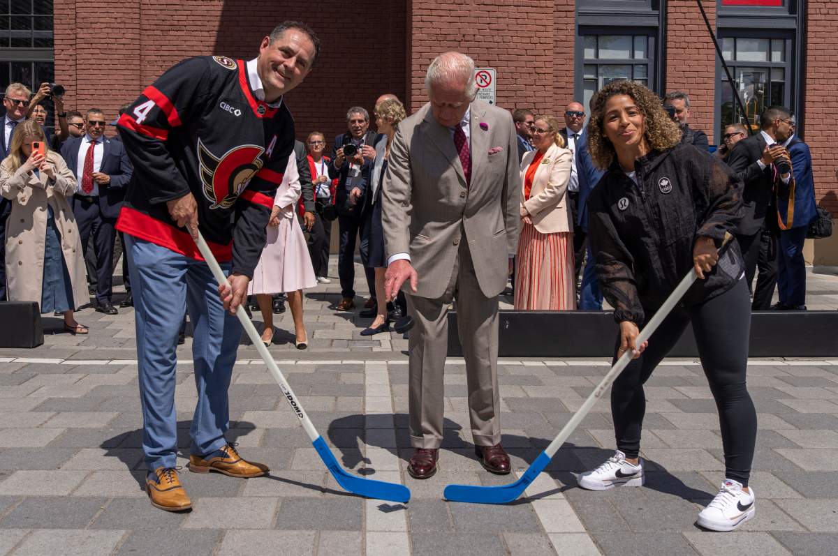 King Charles participate in a ceremonial puck drop with street hockey captains Chris Phillips, left and Desiree Scott during a visit to Lansdowne Park in Ottawa on Monday, May 26, 2025. THE CANADIAN PRESS/Christinne Muschi