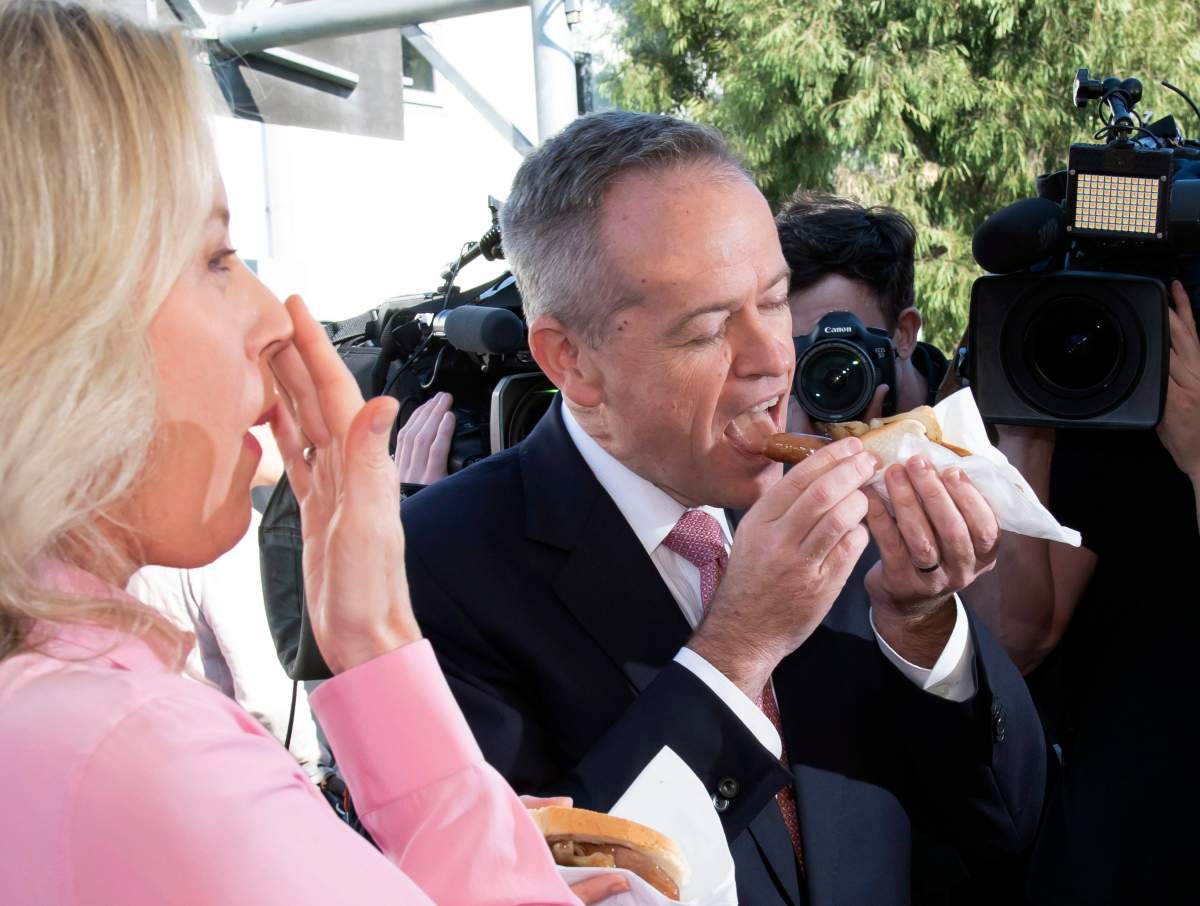 Australian opposition leader Bill Shorten and his wife Chloe eat a sausage sandwich on a federal election day in Melbourne, Australia, Saturday, May 18, 2019.