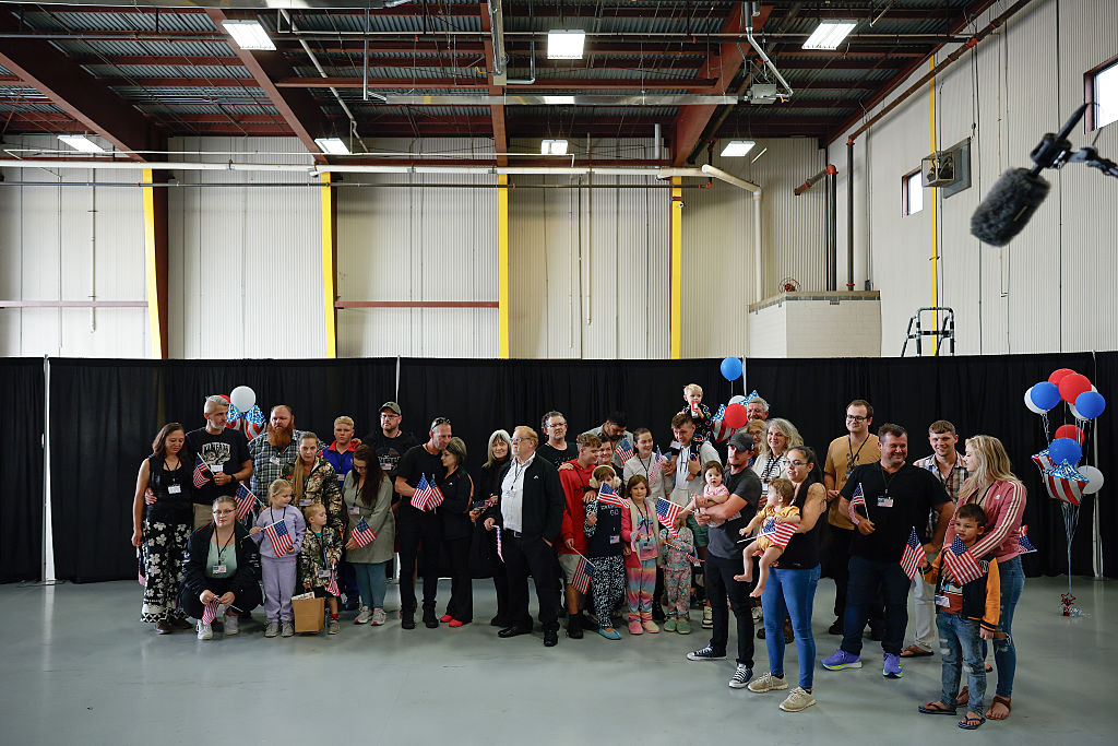 Newly arrived South Africans wait to hear welcome statements from U.S. government officials in a hangar at Atlantic Aviation Dulles near Washington Dulles International Airport on May 12, 2025 in Dulles, Virginia.