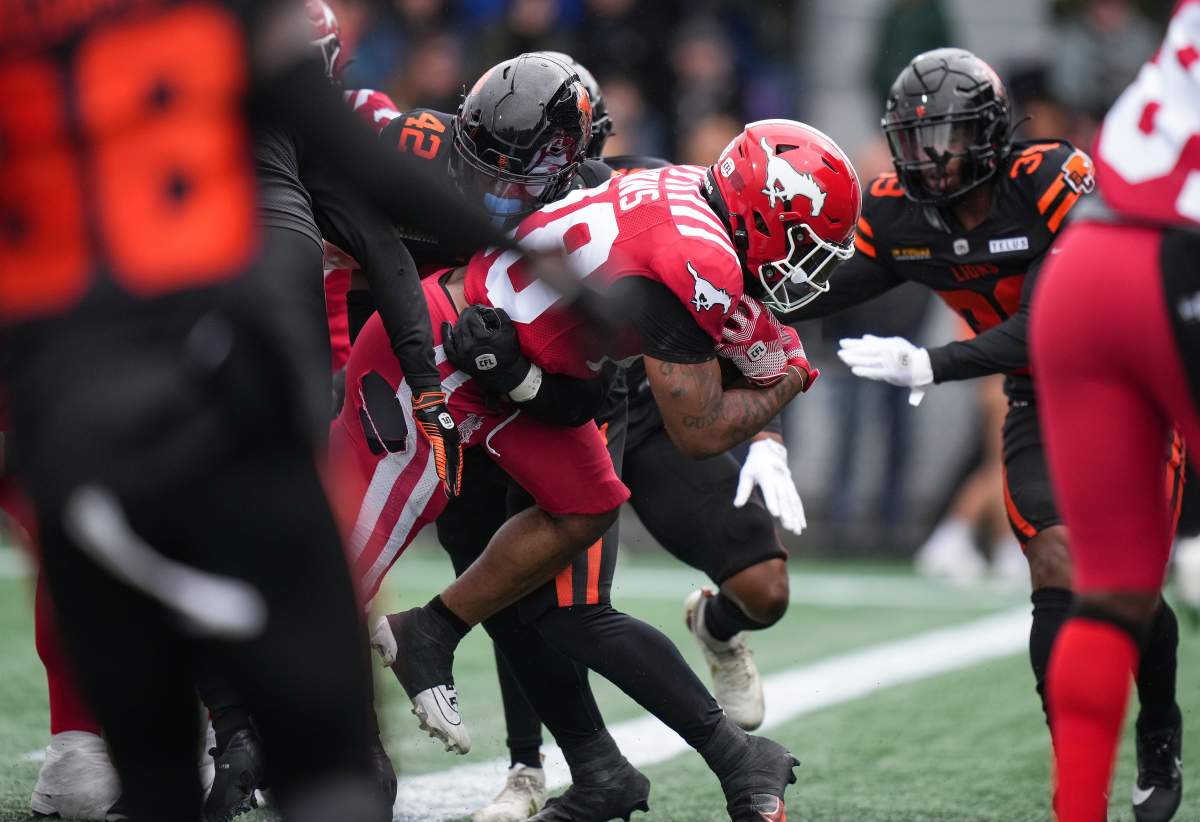 Calgary Stampeders' Tiyon Evans, centre, rushes for a touchdown past B.C. Lions' Mike Smith Jr. (42) during the second half of a preseason CFL football game, in Langford, B.C., on Monday, May 19, 2025.