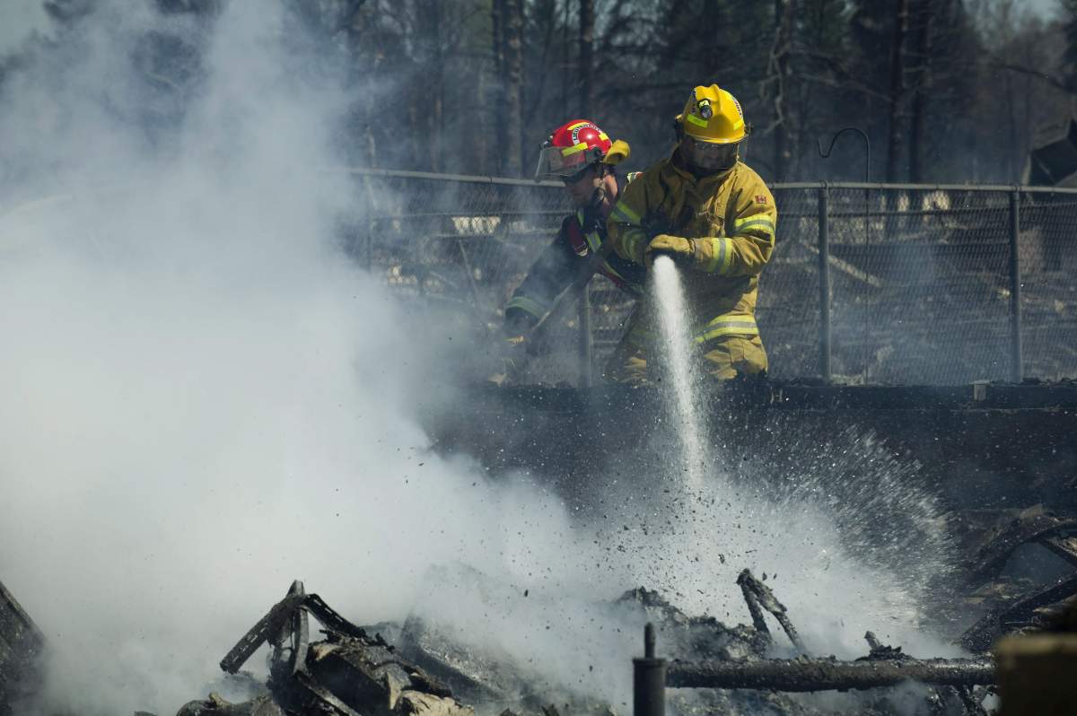 Firefighters work on the smouldering remains of houses in Slave Lake, Alberta, on Monday, May 16, 2011.