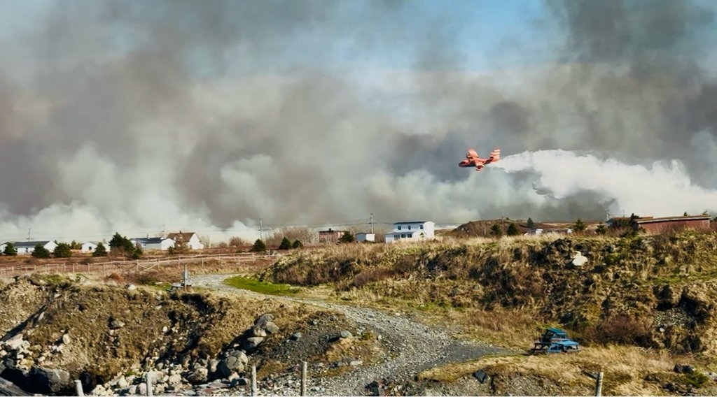A water bomber aircraft douses a wildfire close to homes near Western Bay, N.L., in this Wednesday, May 7, 2025, handout photo. THE CANADIAN PRESS/HO, Eugene Howell *MANDATORY CREDIT*.