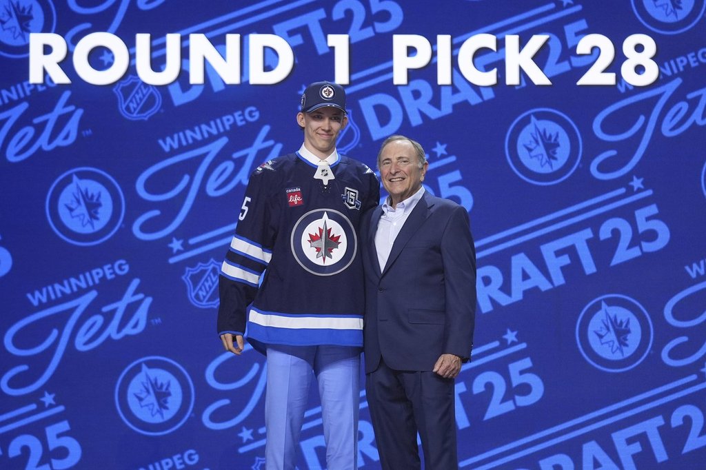 Sascha Boumedienne, left, stands with NHL commissioner Gary Bettman after being drafted by the Winnipeg Jets during the NHL hockey draft Friday, June 27, 2025, in Los Angeles. (AP Photo/Damian Dovarganes).