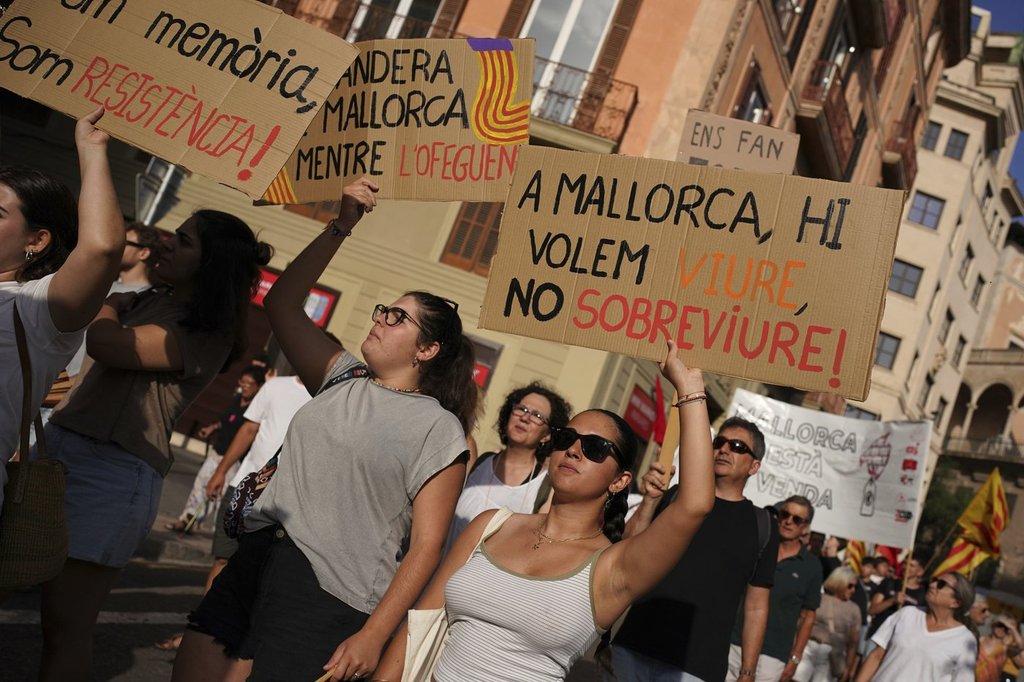 People march during a protest against overtourism in the Balearic island of Mallorca, Spain, Sunday, June 15, 2025. The placards in Mallorquin read, ‘In Mallorca we want to live, not survive’. (AP Photo/Joan Mateu Parra)