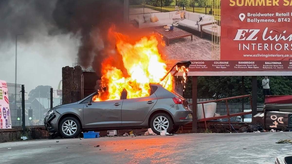 In this image taken from PA Video of a vehicle on fire near Clonavon Terrace, in Ballymena, Northern Ireland, as people take part in a protest over an alleged sexual assault in the Co Antrim town, Tuesday June 10, 2025. (Niall Carson/PA via AP)