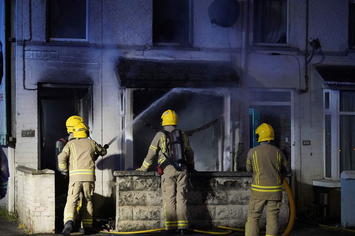 Emergency services work outside a house in Ballymena, Northern Ireland, as people protest over an alleged sexual assault in the Co Antrim town, Tuesday, June 10, 2025, and police used water cannons to disperse protesters engaged in serious disorder for a second night. (Niall Carson/PA via AP)