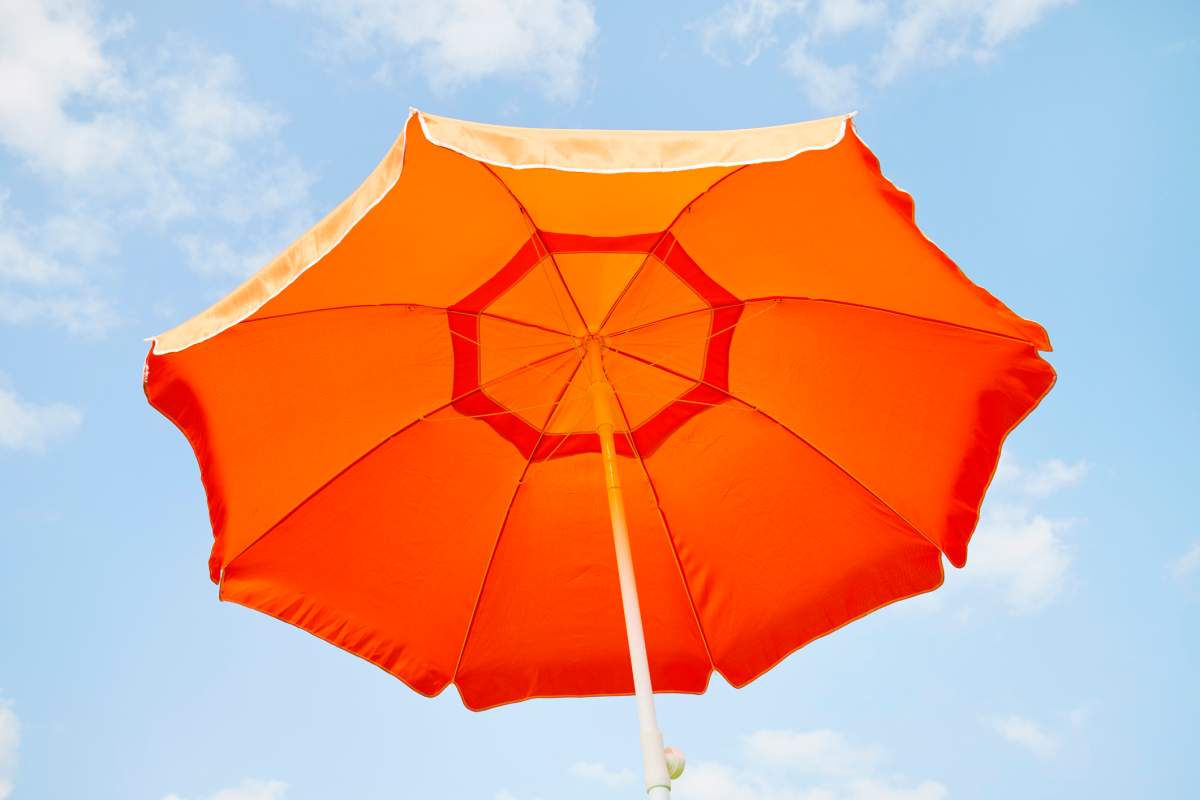 Low angle view of orange parasol against blue sky and clouds