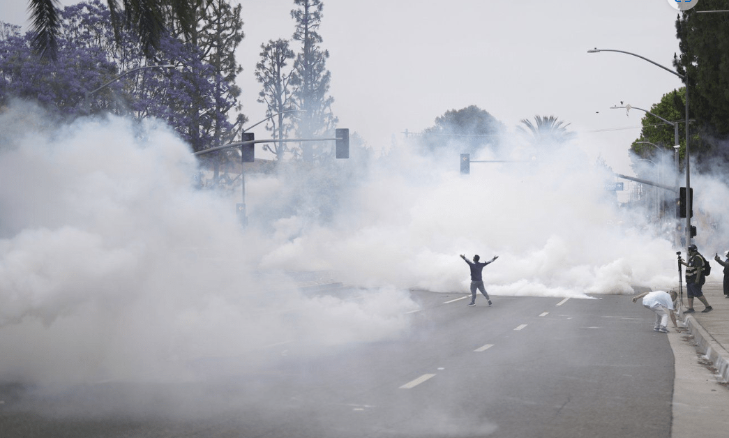 Smoke fills the street as protesters confront Border Patrol personnel during a demonstration over the dozens detained in an operation by federal immigration authorities a day earlier in Paramount section of Los Angeles Saturday.