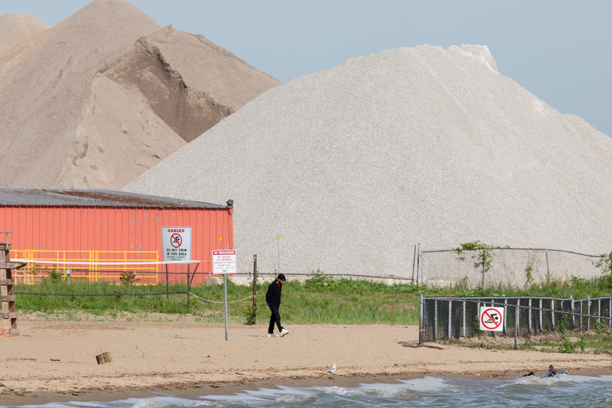 A lone man walks along the shore at Sandpoint Beach in Windsor, Ont. Two males in their 20s went missing while swimming at the beach on May 24, 2024.