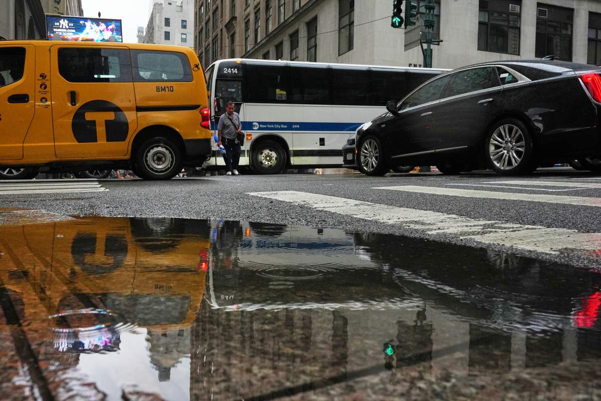 A pedestrians makes his way through cars on Fifth avenue during a rain storm Thursday, July 31, 2025, in New York. (AP Photo/Frank Franklin II)
