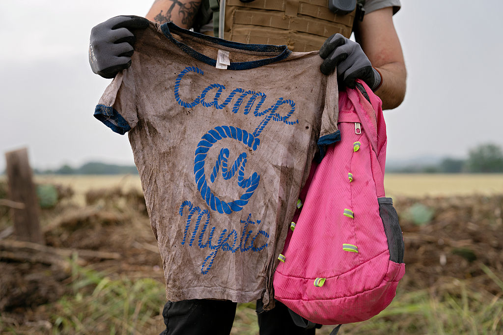 A search and rescue volunteer holds a T-shirt and backpack with the words Camp Mystic on them in Comfort, Texas on July 6, 2025. The volunteer found the belongings yesterday along the Guadalupe River near Ingram, Texas.