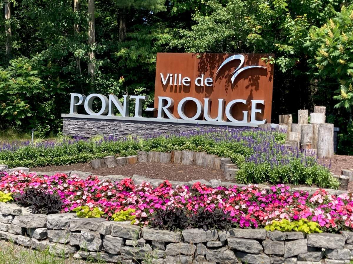 Photo of town sign with colorful bed of rocky flower gardens
