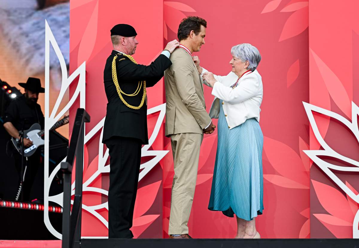 Canadian-American actor Ryan Reynolds, centre, is invested as an Officer to the Order of Canada by Gov. Gen. Mary Simon, right, during Canada Day celebrations at LeBreton Flats in Ottawa, on Tuesday, July 1, 2025.