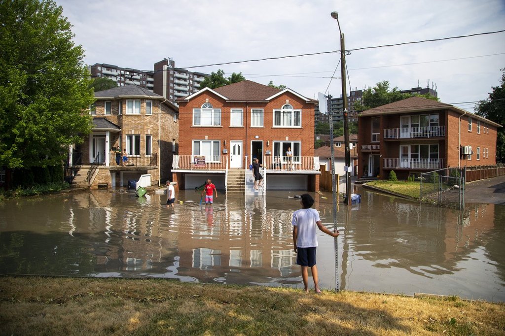 Neighbours deal with the flooding on Cordella Avenue after a severe thunderstorm caused localized flooding in Toronto on Wednesday, July 8, 2020. THE CANADIAN PRESS/Carlos Osorio.