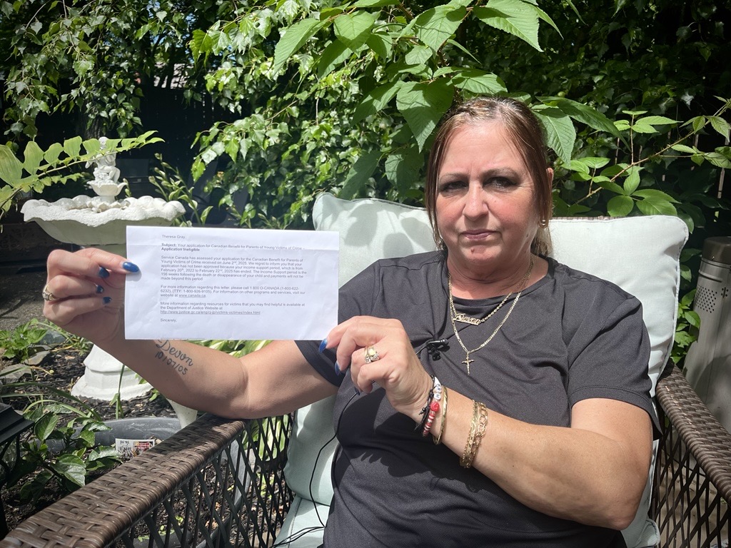 Theresa Gray holds up a letter from the federal government informing her that her application for the Canadian Benefit for Parents of Young Victims of Crime was denied.