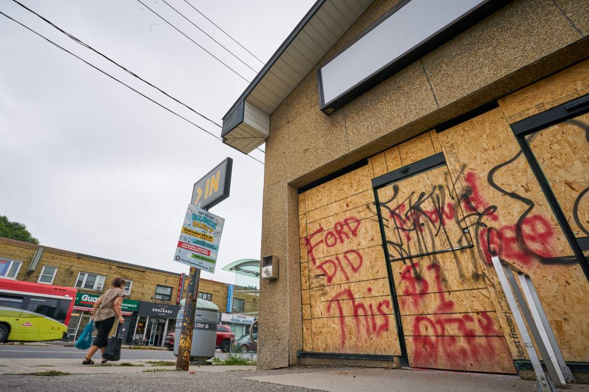 Pedestrians pass by a shuttered Beer Store location graffitied with “Ford Did This” in Toronto’s east end, on Tuesday, August 19, 2025.