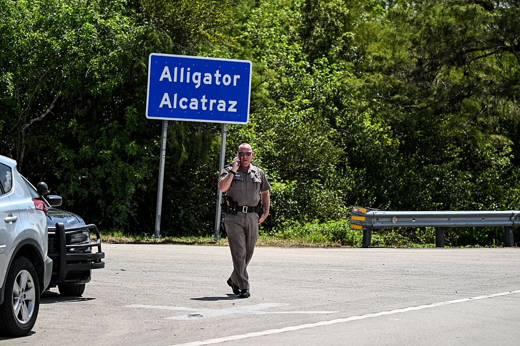 A Florida Highway Patrol officer looks on as protesters gather to demand the closure of the immigrant detention center known as "Alligator Alcatraz" at the Dade-Collier Training and Transition Airport in Ochopee, Florida, on July 22, 2025. Immigrants held at US detention centers have experienced abusive and degrading treatment, a Human Rights Watch report said on July 21.