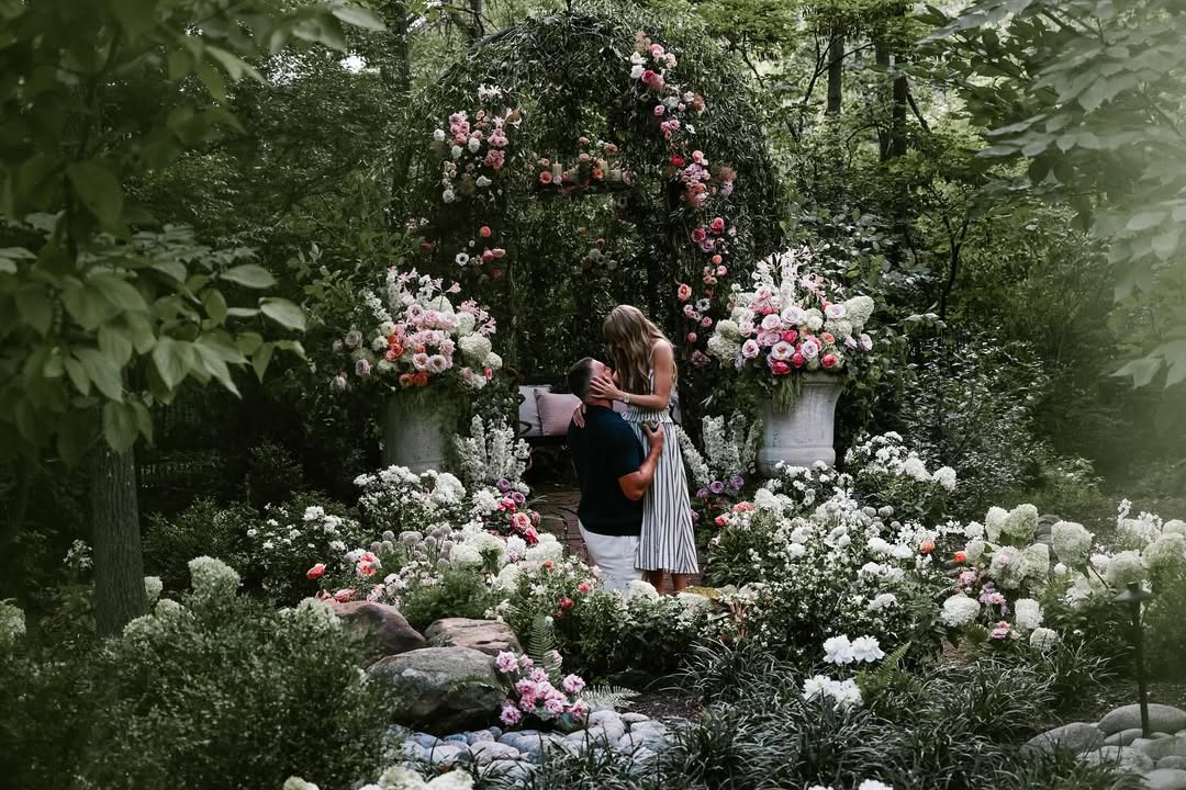 Travis Kelce kneels before Taylor Swift in the first image. The two are in a garden, surrounded by flowers, with Kelce gazing lovingly at the popstar.
