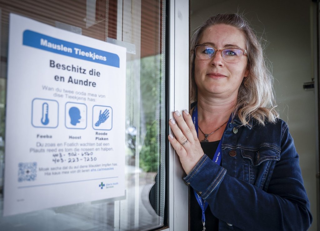 Tina Meggison, a community health rep for the Low German Mennonite community in southern Alberta, is seen with a sign in Low German at the Taber Community Health Clinic in Taber, Alta., Monday, July 28, 2025. 