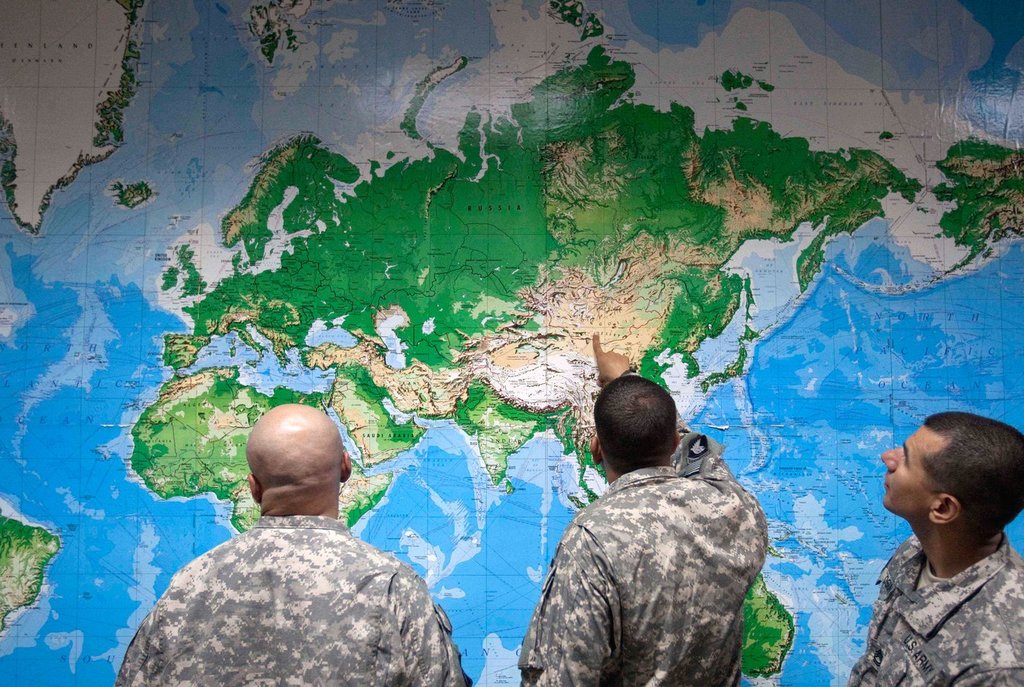 FILE - Soldiers look at a world map as they wait to board a flight in Manas, Kyrgyzstan, on the way home after completing a deployment in Afghanistan, Thursday, Aug. 11, 2011. (AP Photo/David Goldman, file).