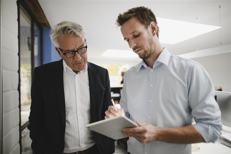 A manager reviews information on an employee’s digital tablet. Westend61/Getty Images