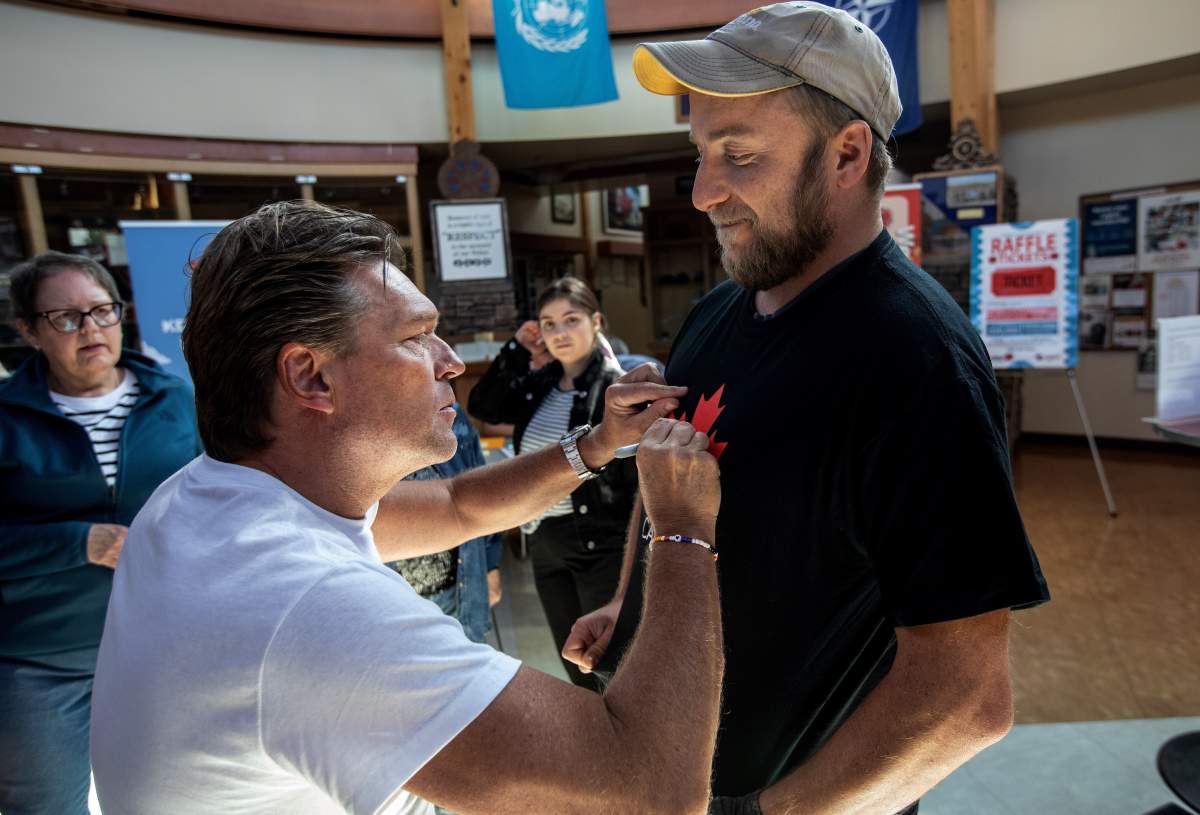 Former conservative deputy premier and head organizer of the Forever Canadian petition, Thomas Lukaszuk signs the shirt of supporter James Levac in Edmonton on Thursday August 21, 2025.