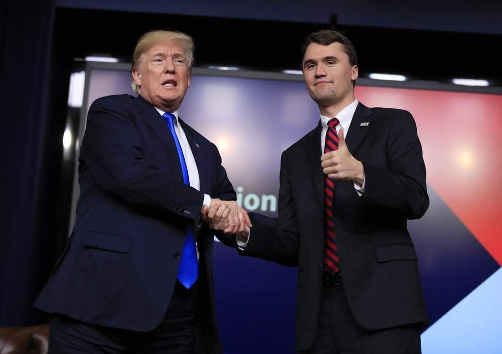 FILE - President Donald Trump shakes hands with moderator Charlie Kirk, during a Generation Next White House forum at the Eisenhower Executive Office Building on the White House complex in Washington, Thursday, March 22, 2018.