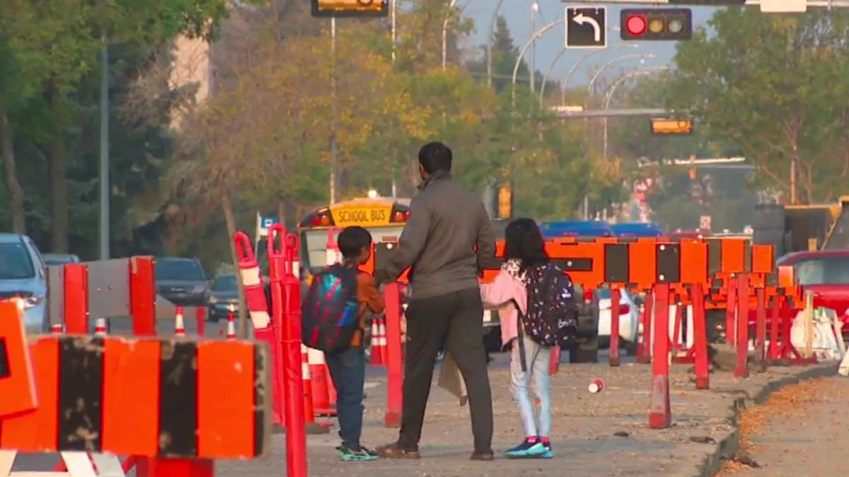 A parent trying to cross the road with his kids amid heavy road construction in west Edmonton's Meadowlark area on Tuesday, Sept. 9, 2025.