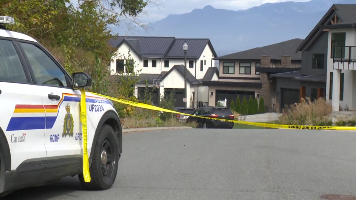 A police vehicle with yellow police tape in front of a row of houses