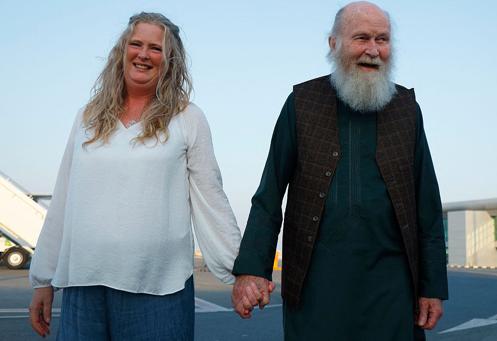 Peter Reynolds (R) holds the hands of his daughter Sarah Entwistle after landing at the airport in Doha on September 19, 2025.