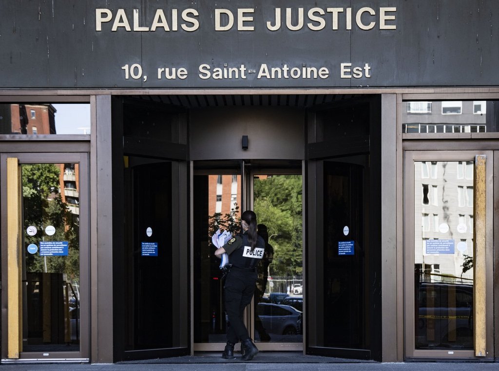 A police officer carries paperwork into the Palais de Justice, Quebec Superior Court, in Montreal on Monday, Aug. 18, 2025. THE CANADIAN PRESS/Christinne Muschi.