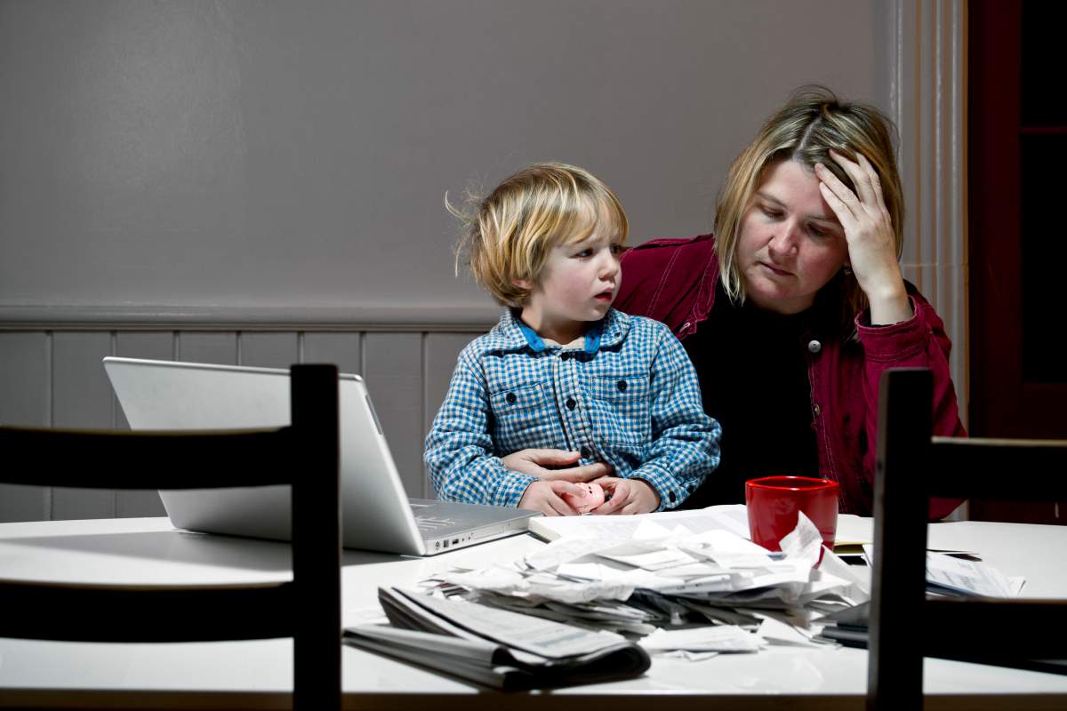 A mother rubs her forehead after receiving a denial letter from her insurance company.