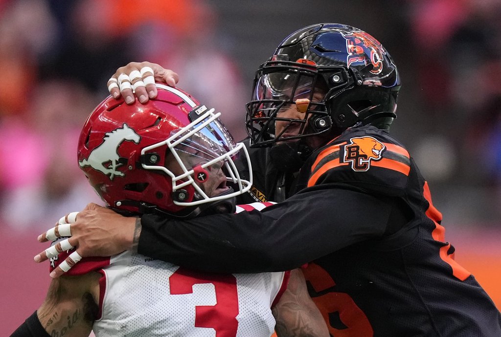 Calgary Stampeders quarterback Vernon Adams Jr., left, is hit by B.C. Lions' Bradlee Anae after releasing the ball during the first half of a CFL football game, in Vancouver, on Saturday, Oct. 4, 2025. THE CANADIAN PRESS/Darryl Dyck.