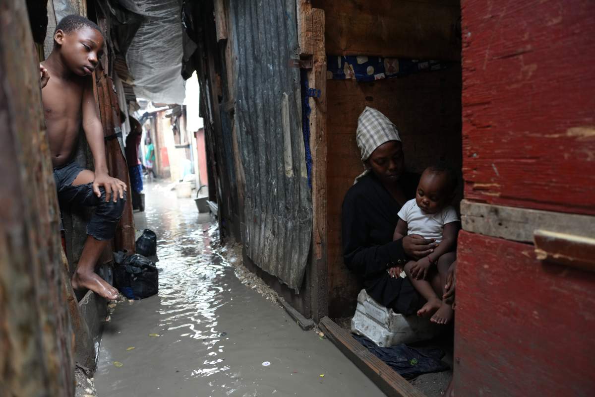 People stay inside a shelter for families displaced by gang violence, flooded by rain brought by Hurricane Melissa, in Port-au-Prince, Haiti, Wednesday, Oct. 29, 2025.