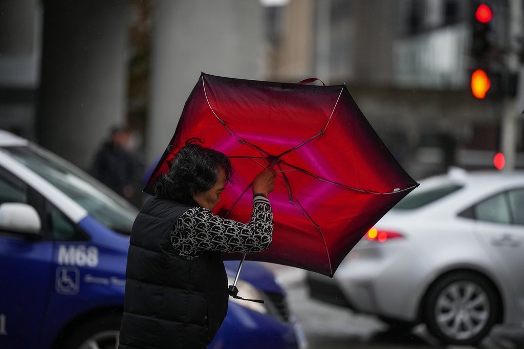 A woman struggles with an umbrella in the wind as rain falls in Vancouver on Monday, Sept.25, 2023. THE CANADIAN PRESS/Darryl Dyck.