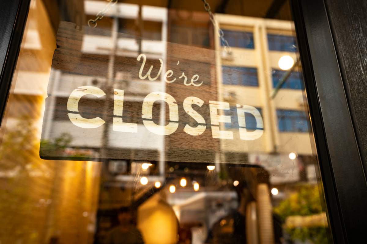 A business uses a wooden sign to tell customers that it’s closed.