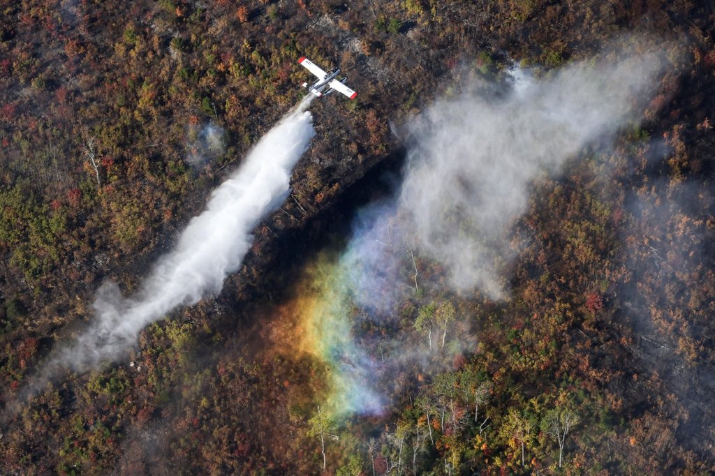 A plane from the Northwest Territories makes a drop over the Lake George wildfire near Aylesford, N.S. in this Friday, Oct. 3, 2025 handout photo. 