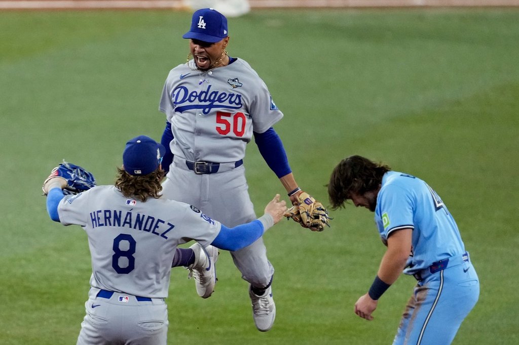 Los Angeles Dodgers’ Mookie Betts (50) leaps into the arms of Kiké Hernández (8) after Toronto Blue Jays’ Addison Barger, right, was forced out to end Game 6 of baseball’s World Series, Friday, Oct. 31, 2025, in Toronto.