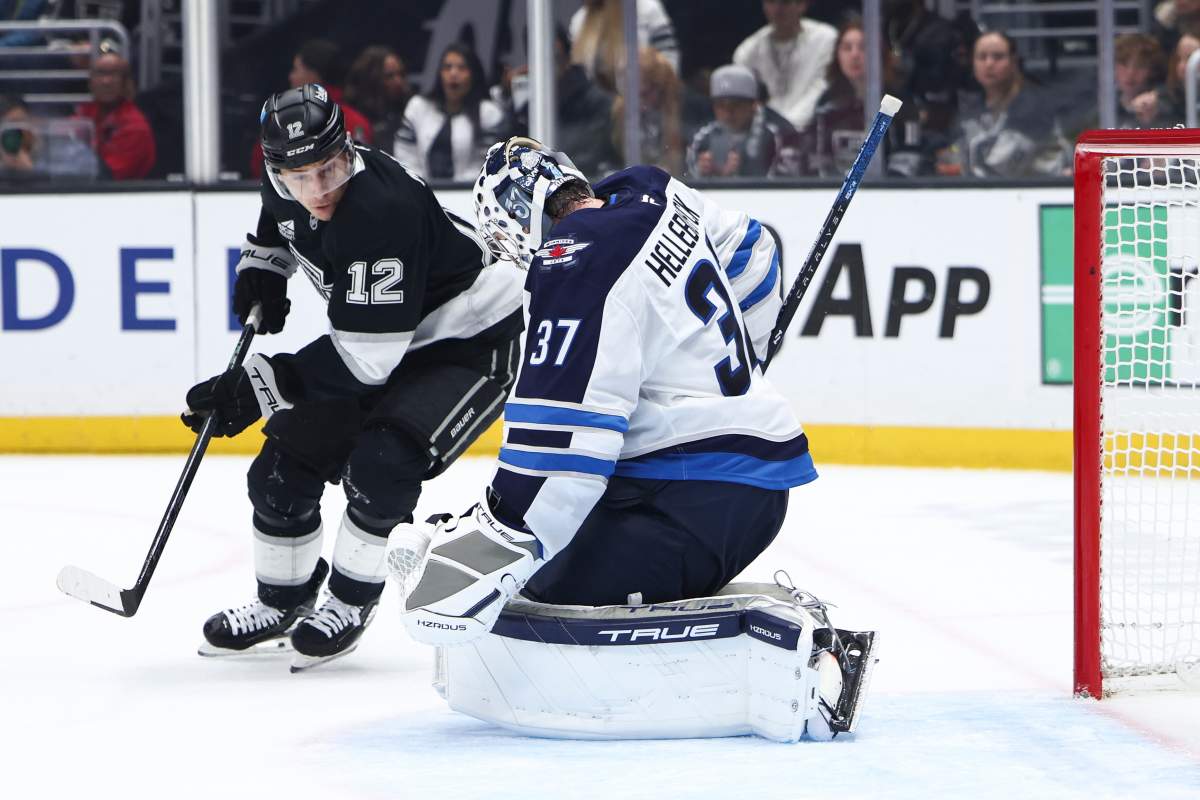 Winnipeg Jets goaltender Connor Hellebuyck (37) makes a save as Los Angeles Kings left wing Trevor Moore (12) watches during the second period of an NHL hockey game, Tuesday, Nov. 4, 2025, in Los Angeles. (AP Photo/Jessie Alcheh).