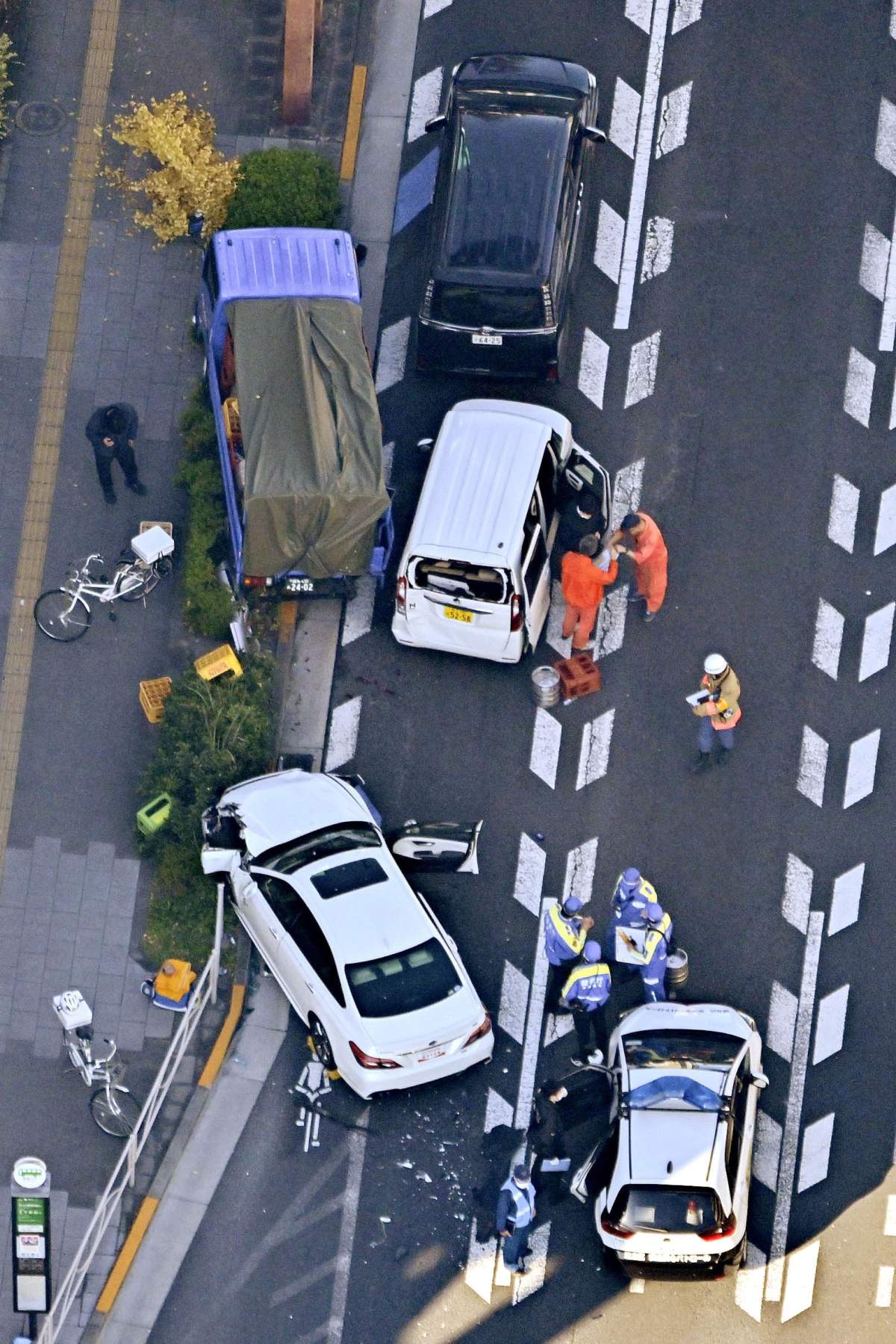 Investigators inspect the scene of a car accident injuring multiple people and damaging several vehicles in Tokyo, Monday, Nov. 24, 2025. (Kyodo News via AP)