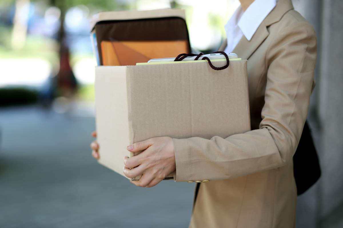 A businesswoman holding her office supplies in a cardboard box. RUNSTUDIO/Getty Images