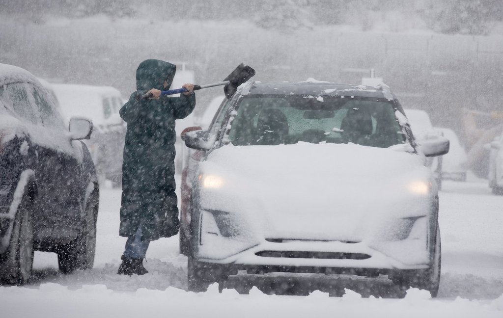 A commuter wipes off their vehicle amid heavy snowfall in St. John's, Wednesday, Dec. 3, 2025.