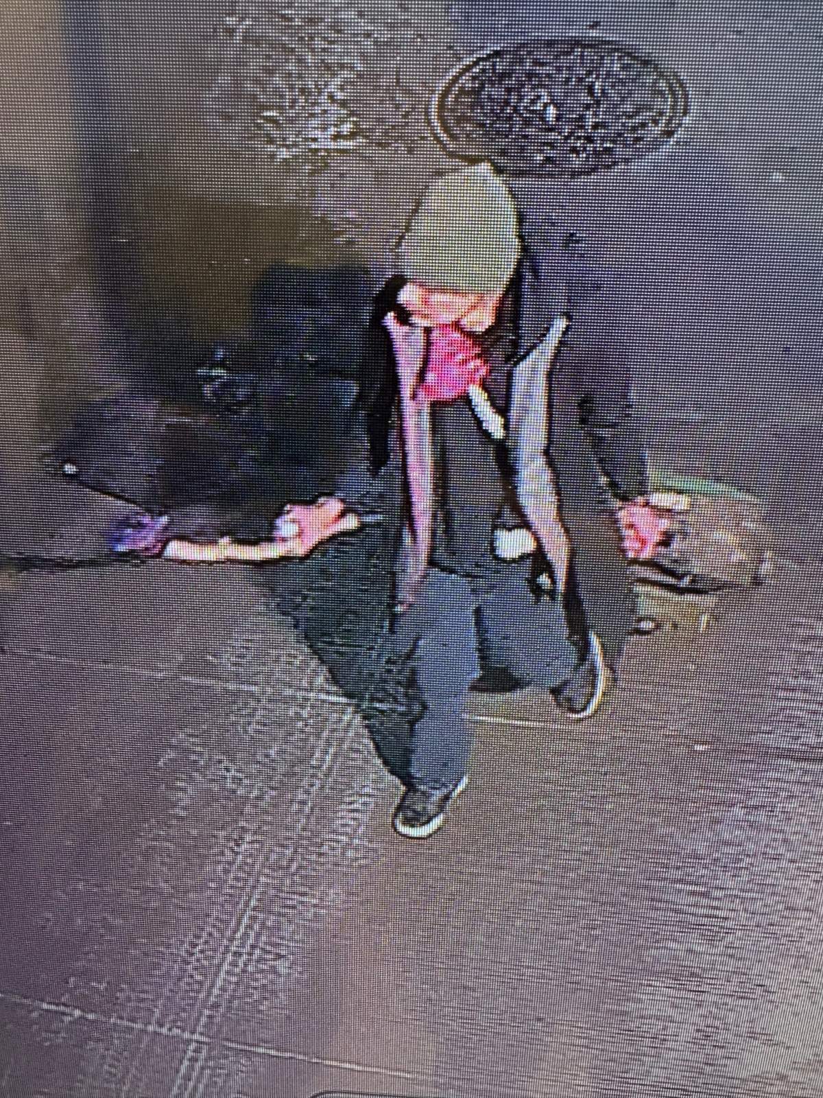 A man walking carrying a stick that is on fire.