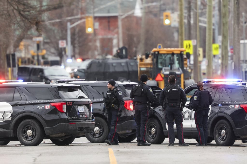 Members of Niagara Regional Police position themselves along Plymouth Road, close to the location where an officer was shot in Welland, Ont., while police were responding to reports of gunfire, Friday, Dec. 19, 2025. 