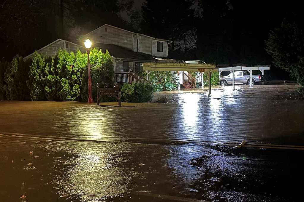 Waters from a rising and muddy Issaquah Creek flood a parking lot of an evacuated apartment building near downtown Issaquah, Wash., on Dec. 11, 2025. (AP Photo/Martha Bellisle)