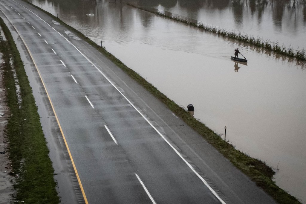 A man paddles down floodwaters along Highway 1 in Abbotsford, B.C., on Friday, Dec. 12, 2025. THE CANADIAN PRESS/Ethan Cairns.